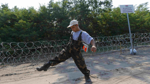 Un soldado húngaro da un salto durante los trabajos de construcción de una cerca de alambre de púas cerca Ásotthalom, Hungría.-REUTERS / Laszlo Balogh TPX IMÁGENES DEL DÍA