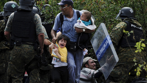 Dos niños sirios lloran entre las cargas de la policía contra los refugiados en la frontera entre Grecia y Macedonia.- REUTERS/Ognen Teofilovski