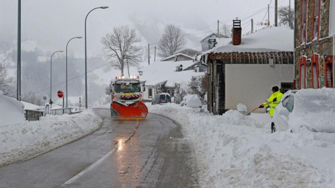 Un vecino del pueblo de Pajares (Asturias) trata de abrir con una pala el camino para sacar su vehiculo ante una camion que limpia la carretera. /EFE