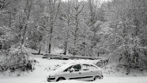 Un coche permanece atascado en la nieve en el Alto de Mezquiriz donde, tras el último temporal de nieve, frío y viento. /EFE