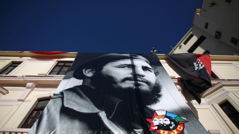 Un hombre despliega en la fachade de un edificio de La Habana un enorme retraro de Fidel Castro, para celebrar su 90 cumpleaños. REUTERS/Alexandre Meneghini