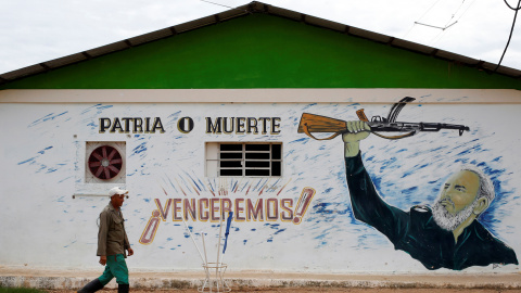 Un hombre pasa junto a un edificio en la localidad cubana de Bauta, en cuya fachada hay pintado un retrato de Fidel Castro con el lema 'Patria o Muerte ¡Venceremos!'. REUTERS/Stringer