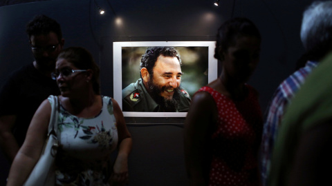 Varias personas junto a uno de los retratos del líder de la revolución cubana, Fidel Castro, que forman parte de la exposición 'Fidel', con motivo de su 90 cumpleaños. REUTERS/Alexandre Meneghini