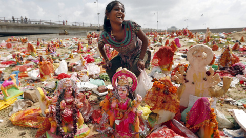 Una mujer recoge figuras de la diosa hindú Dashama, dejados por los devotos a orillas del río Sabarmati en el décimo y último día del festival dashama en Ahmedabad, India, 24 de agosto de 2015. REUTERS / Dave Amit