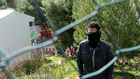 Un migrante tapa su rostro mientras aguarda en el Centro de Recepción de Inmigrantes de Lampedusa.- AFP