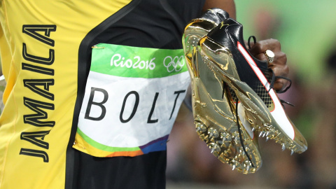 El atleta jamaicano Usain Bolt con sus zapatilas en la mano tras vencer en la carrera de 100 metros en los JJOO de Río. REUTERS/Phil Noble