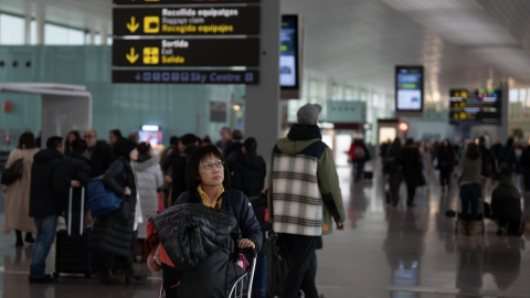 Una mujer transporta en un carro sus maletas en el aeropuerto de El Prat, a 19 de enero de 2023.