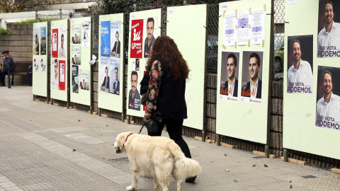 Una mujer pasa por delante de carteles electorales de los distintos candidatos a Presidente de Gobierno para las elecciones generales del próximo domingo en Santurce (Vizcaya), durante la campaña electoral para las elecciones generales del 