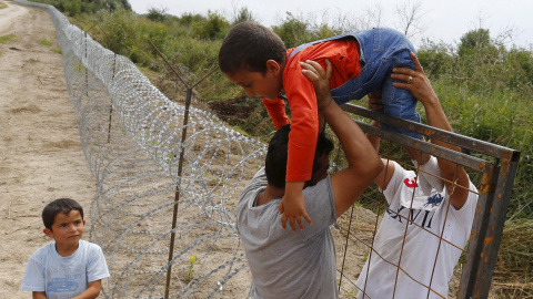 Refugiados kurdos sirios pasan un niño sobre una cerca en la frontera húngaro-serbia, cerca Ásotthalom, Hungría .- REUTERS / Laszlo Balogh