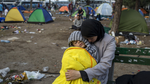 Una refugiada siria sujeta a su hijo mientras duerme en un parque con un niño duerme en un parque cerca de la principal estación de autobuses y de tren en Belgrado, Serbia, después de días caminando desde Macedonia para llegar al norte de E