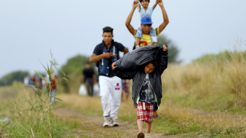 Refugiados sirios, muchos de ellos niños, caminan después de cruzar la frontera húngaro-serbio en Hungría, cerca Röszke, y sortear la alambrada de cuchillas recién instalada.-REUTERS / Laszlo Balogh