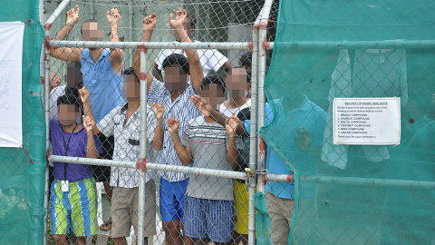 Refugiados miran desde la valla del centro de detención en la Isla de Manus.  REUTERS