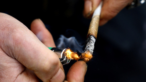 Una persona enciende un cigarrillo de marihuana en una concentración por la legalización del cannabis frente a la Puerta de Brandenburgo, en Berlín, en abril de 2022. — REUTERS/Lisi Niesner /