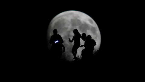 La silueta de grupo de excursionistas recortada ante la Luna, en Tijuana, México.- JORGE DUENES (REUTERS)