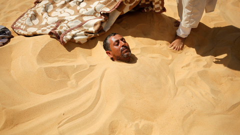 Un hombre se toma un baño de arena en Siwa, en el oeste de Egipto. Los nativos creen que los baños de arena son una terapia natural con poderes para curar muchas enfermedades.- ASMAA WAGUIH (REUTERS)