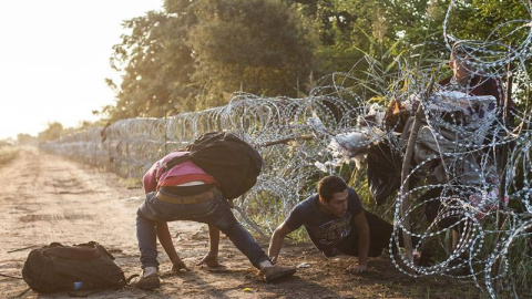 Varios refugiado pasan la alambrada en la frontera entre Hungría y Serbia cerca de Roszke (Hungría). / SANDOR UJVARI (EFE)