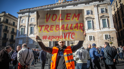 Un conductor de VTC porta un cartel con la consigna "Volem Treballar #apoyoVTC" en la Plaza de Sant Jaume - David Zorrakino/ EP