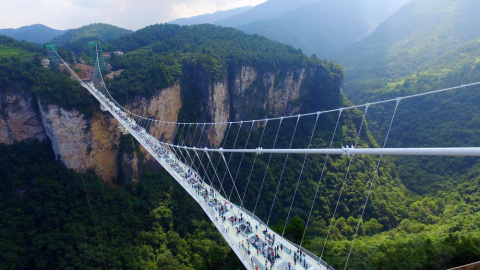 Los turistas caminan por el puente colgante con el suelo de cristal, en el parque natural de Zhangjiajie, en la provincia china de Hunan. EFE / EPA / Shao Ying