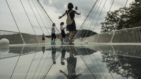 Una turista se hace un selfie sobre puente de cristal más largo y más alto del mundo sobre el valle del parque natural de Zhangjiajie, en la provincia china de Hunan. AFP/FRED DUFOUR