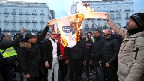 Los taxistas queman un cartel del PP con la cara del presidente de la Comunidad de Madrid en  segundo día consecutivo en la madrileña Puerta del Sol. (KIKO HUESCA | EFE)