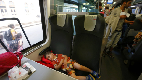 Un niño duerme en los asientos del tren a la espera de que el convoy parta con destino a Austria y Alemania. REUTERS