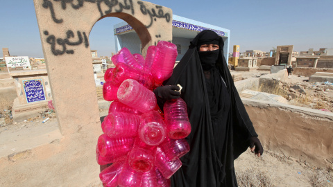 Una mujer lleva los bidones de agua que se emplean para limpiar las tumbas del  cementerio de Wadi al-Salam ('Valle de la Paz'), en Najaf, al sur de Bagdad. REUTERS/Alaa Al-Marjani