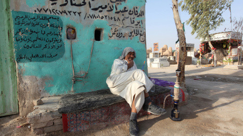 Un enterrador fuma una 'shisha' en el cementerio de Wadi al-Salam (el 'Valle de la Paz'), en Nayaf, al sur de Bagdad. REUTERS / Alaa Al-Marjani