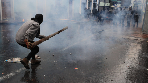 Miembros policiales avanzan entre el humo hacia un manifestante./ José Jácome (EFE).