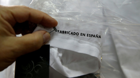 Un trabajador sostiene una etiqueta que pone 'Hecho en España' en una camisa en una fábrica textil en Madrid. REUTERS/Andrea Comas