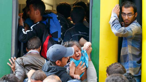 Variso refugiados sirios intentan subirse a un tren en la estación de Budapest. / LAZSLO BALOGH (REUTERS)