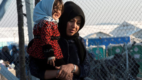 Una mujer carga a su bebé mientras se dirige al centro de registro de migrantes tras cruzar la frontera entre Macedonia y Grecua, en Macedonia. EFE