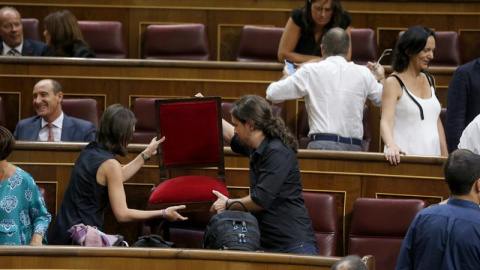 Los dirigentes de Podemos Pablo Iglesias (d) e Irene Montero (i) se acomodan en el hemiciclo poco antes del comienzo de la primera jornada del debate de investidura a la que se someterá el presidente del Gobierno en funciones, Mariano Rajoy