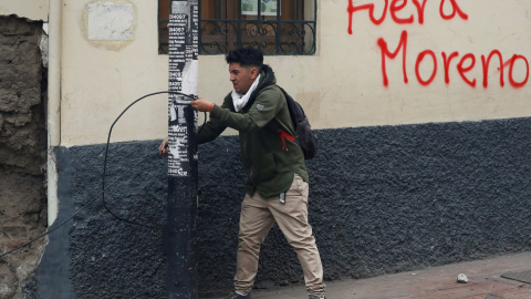 Un manifestante tira de un cable al lado de un graffiti donde se puede leer 'Moreno fuera'. REUTERS/Carlos Garcia Rawlins