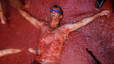 Uno de los participantes en la Tomatina de Buñol, tumbado sobre la pulpa de tomate en la calle. REUTERS / Heino Kalis