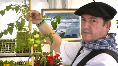 Un "baserritarra" (agricultor) muestra una mata de tomate en la inauguración de una feria de agricultura en Bilbao. / EFE