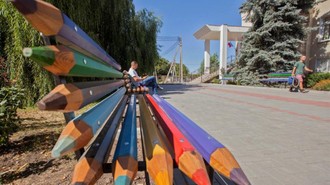 Un hombre sienta en un banquillo hecho de lápices de color cerca de un colegio en Ialoveni, a 15 kilómetros de Chisináu, Moldavia. Se celebra el Día Nacional del Idioma Moldavo desde 1989. EFE/Dumitru Doru