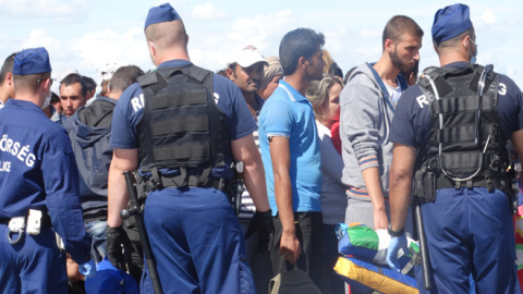 La policía rodea a los refugiados que acaban de cruzar la frontera. / CORINA TULBURE