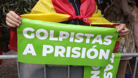 Una mujer sujeta un cartel de color verde en el que se puede leer: "Golpistas a prisión".