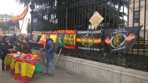 Un hombre vende banderas de España y símbolos de la Policía Nacional y Guardia Civil en los aledaños de Colón