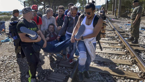 Un grupo de refugiados atraviesan la frontera entre Grecia y Macedonia, auxiliando a otro migrante. La mayoría proceden de Siria y atraviesan el autodenominado 'corredor de los Balcanes'. EFE/EPA/GEORGI LICOVSKI