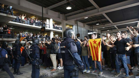 Miembros de la Policía Nacional controlan en la zona de parada de autobuses a los manifestantes independentistas que van llegando al Aeropuerto del Prat. (QUIQUE GARCÍA | EFE)