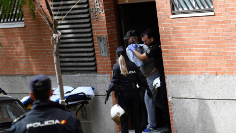 Agentes de la Policía Nacional reducen y sacan de la vivienda al hombre que se había atrincherado con una mujer este lunes en un piso en Leganés (Madrid). /EFE