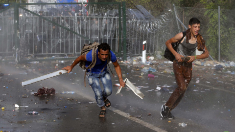 Un grupo de inmigrantes protesta en la frontera mientras la Policía húngara les rocía con gases y cañones de agua. REUTERS