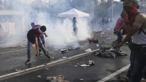 Migrantes se cubren la cara para protegerse de los gases lacrimógenos utilizados por la policía antidisturbios húngara en la parte serbia de la frontera, cerca de Röszke. REUTERS