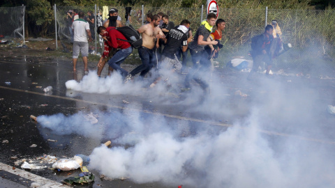 Un migrantes húngaro protesta con un megáfono mientras los antidisturbios húngaros rocían con gases lacrimógenos y cañones de agua a los refugiados. REUTERS