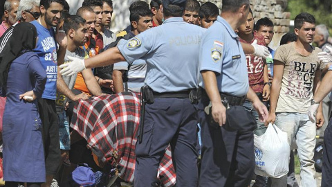 Policías croatas dirigen a varios refugiados a un autobús que les trasladará a un centro de acogida, tras cruzar la frontera con Serbia. - EFE