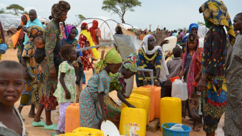 Una mujer reparte agua en un campo de refugiados que han tenido que huir por la violencia de Boko Haram. - AFP