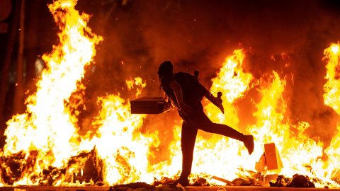 15/10/2019.- Un manifestante echa al fuego un cartón junto a la Delegación del Gobierno en Barcelona durante los incidentes producidos al finalizar la movilización convocada por los CDR, hoy martes en la segunda jornada de protestas contra 