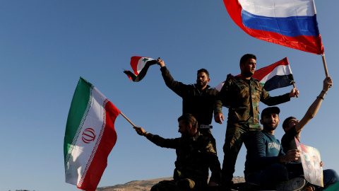 Sirios ondean las banderas de Irán, Rusia y Siria en protesta por los ataques en Damasco. /REUTERS