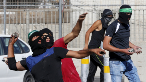 Los palestinos lanzan piedras hacia la policía fronteriza israelí durante los enfrentamientos en un puesto de control entre el campamento de refugiados de Shuafat y Jerusalén./ REUTERS/ Ammar Awad